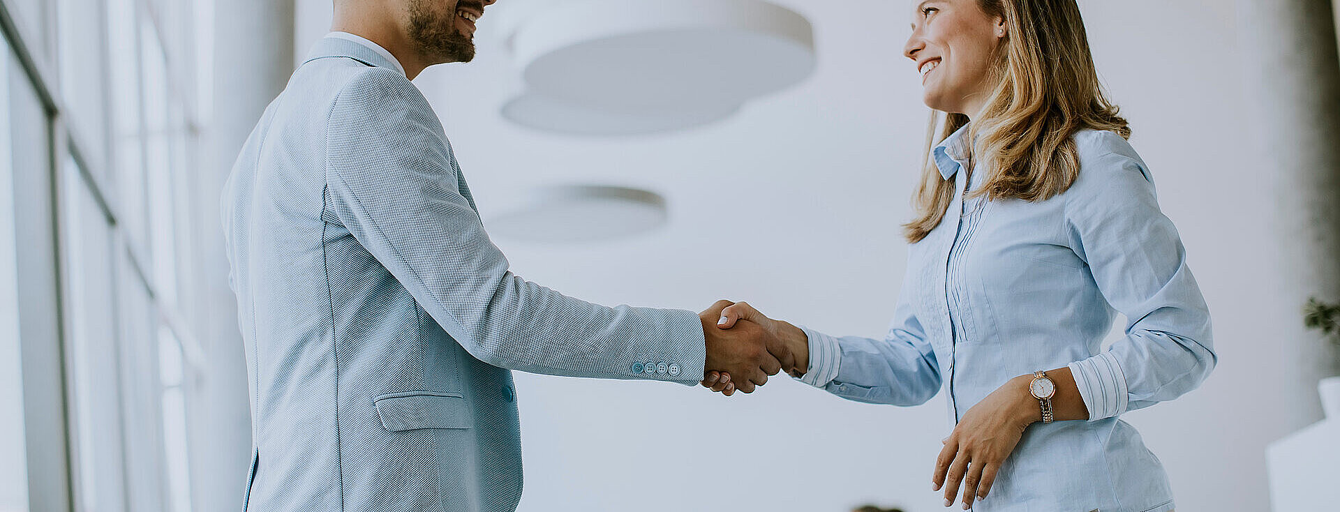 Young business couple handshaking in the office Handschlag zweier junger Personen im Büro