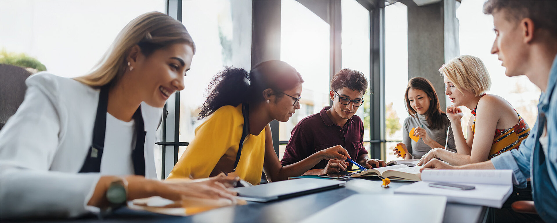 Junge Personen sitzen gemeinsam am Tisch und lernen